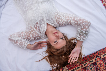 Top view close up portraityoung millennial woman lying on a white bed with her hair disheveled.