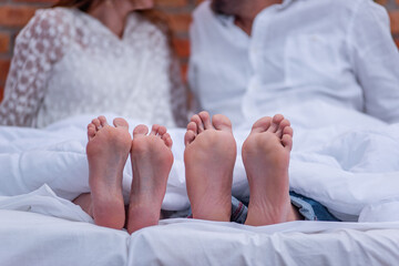 From under the white she covered two pairs of feet of couple in love. The newlyweds are having fun
