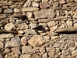 Brown stones textured background. Rough rustic wall with an uneven surface made with rocks of different sizes and shapes piled