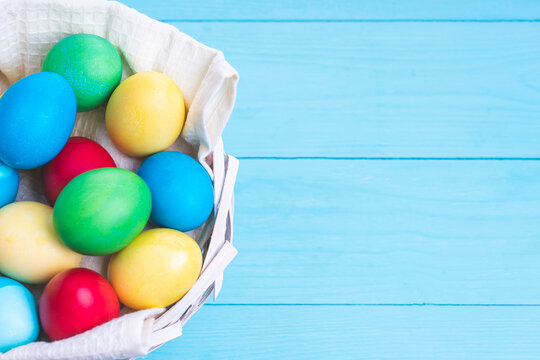 basket with colorful Easter eggs on a blue wooden background, selective focus, tinted image