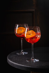 Italian Aperol Spritz cocktail with orange slices on black wooden table. Summer drink, homemade sangria. Copy space