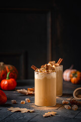 Autumn pumpkin spice latte with whipped cream and cinnamon on dark background