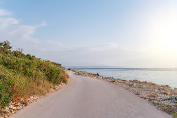Fototapeta na wymiar Country road on the seashore in the rays of sunset. Croatia