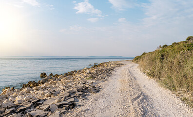 Fototapeta na wymiar Country road on the seashore in the rays of sunset. Croatia