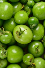 Green tomatoes of different sizes, top view, close-up.