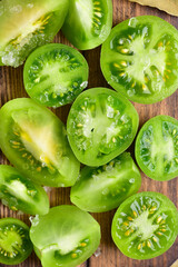 Fototapeta na wymiar Green cut tomatoes on a brown board, top view, close-up.