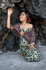 Balinese girl posing in nature and in a forest on Candidasa's offshore islands in Bali, dressed in a traditional costume. 