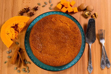 Pumpkin pie on a wooden board, ingredients for making the pie, top view