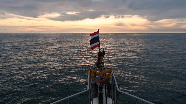 View from scuba diving prow boat with Thai flag on the bow and garland for worship Speedy transport in outdoor tourism in Andaman Sea, beautiful natural landscape, sea sunset or sunrise sky.