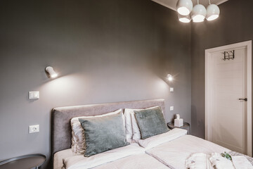 Contemporary interior of bedroom in grey colors. Modern apartment. Queen size bed. Closed door.