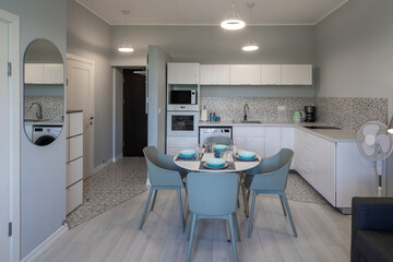 Contemporary interior of modern apartment. Kitchen with appliances. Dinner table. Entrance door.