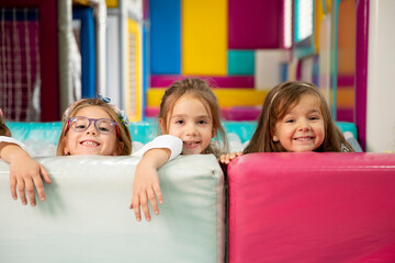 Fototapeta na wymiar Group of cute little girls hiding behind large leather blocks