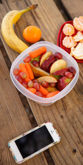 Top view of a modified phone and fruits and vegetables as a snack on a walk or picnic on a warm summer day. Apples, pears, grapes, tangerines, bananas and carrots