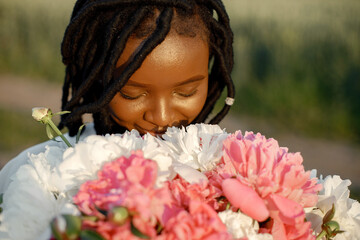 Fototapeta premium Black woman with peony flowers at field
