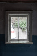 Old dirty white wooden window of an abandoned dark 19th century house. View from the inside.