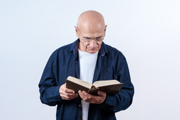 Elder hairless man wearing eyeglasses holding and reading book