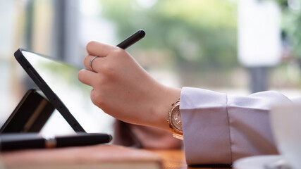 Asian woman hand holding pen stylus writing on digital tablet computer. close up
