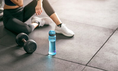 Fitness woman breaking relax after training with dumbbell at gym.