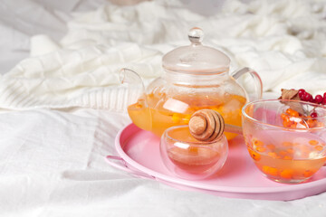 Autumn hot tea with ginger, lemon, honey and sea buckthorn on the bed