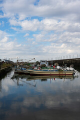 Fototapeta premium 小さな漁港に停泊する小型の漁船が青い空を写す波間に漂う 