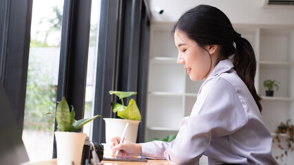 Asian woman hand holding pen stylus writing on digital tablet computer. close up