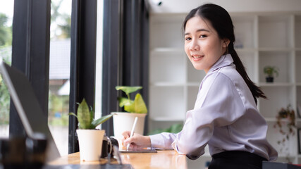 Asian woman hand holding pen stylus writing on digital tablet computer. close up