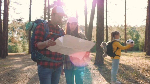 Family on hike. Happy family open map planning a hiking adventure. Group of family travelers in pine forest consulting about the directions with a map. Travel vacations. Family hiking trek concept.