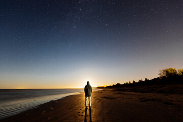 Person walking on the beach under the night sky