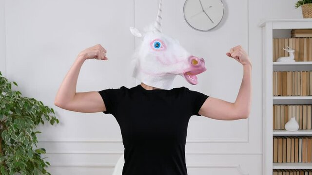 Woman in unicorn head showing sporty strong arms - funny weird video