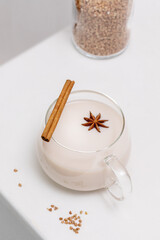 Non lactose buckwheat milk. Vegan food composition with glass cup of plant milk with a cinnamon stick and anise on a white table. Vegan healthy milk products. eco friendly food banner
