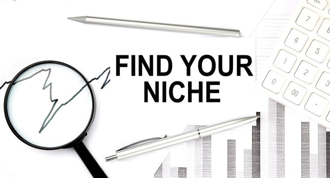 FIND YOUR NICHE text on document with pen,graph and magnifier,calculator