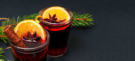 Glasses of alcoholic mulled wine with cinnamon, anise and spruce branches with decorations on a...