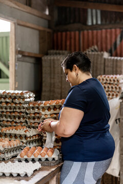 mujer latina con sobrepeso empacando huevos en la granja 