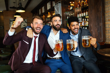 Business men in pub cheering for a sporting event