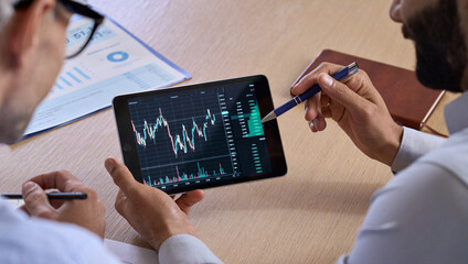 Trader consulting business investor showing crypto trading chart using digital tablet computer...