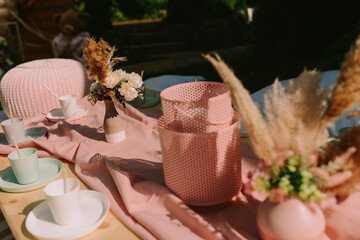 Birthday colorful decoration in the yard - pink plates and pots on a wooden table for celebration