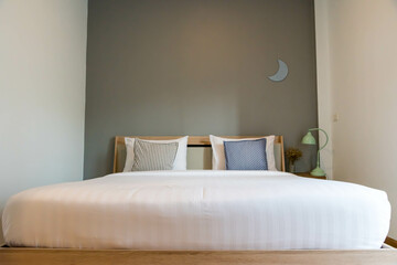 Front view of a modern bedroom  interior with gray walls, a wooden floor and a horizontal poster hanging above a double bed.  minimalist bedroom interior monotone color.