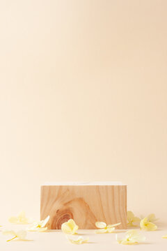 Cosmetic background with wood podium and flowers on pastel beige. Empty showcase for cosmetic product presentation on pastel beige background. Close up, copy space