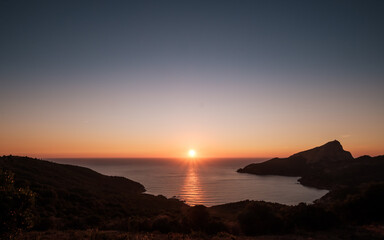 Obraz premium Sun setting over the Genoese tower of Tour de Turghiu sitting on Capo Rosso on the west coast of Corsica