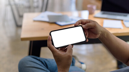 Close up view of man holding smartphone blank white screen for text message or information.