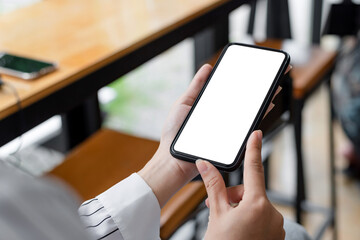 Close up view of woman holding smartphone blank white screen for text message or information.