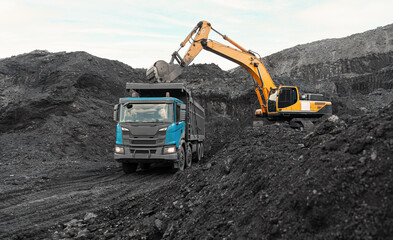 Obraz premium Large quarry dump truck. Loading the rock in dumper. Loading coal into body truck. Production useful minerals. Mining truck mining machinery, to transport coal from open-pit as the Coal Production