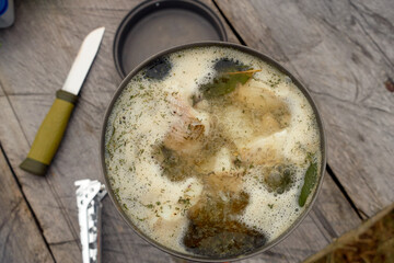 Fish soup in a metal plate on a wooden background. Cooking food on a tourist burner. Traditional food angler or tourist. 
