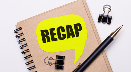 On a light background, a brown notebook, a black pen and paper clips, and a yellow card with the...