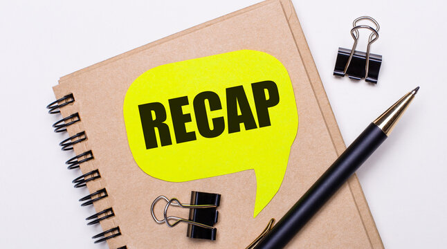 On a light background, a brown notebook, a black pen and paper clips, and a yellow card with the text RECAP.Business concept.