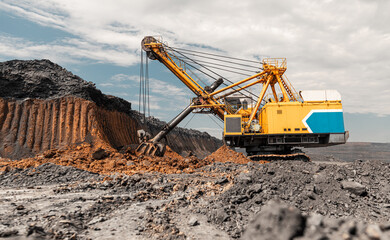 Large quarry dump truck. Big yellow mining truck at work site. Loading coal into body truck. Production useful minerals. Mining truck mining machinery to transport coal from open-pit production