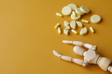Wooden human dummy is lying next to many pills and pills. Concept of drug addiction, withdrawal...