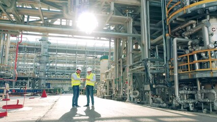 Refinery co-workers are discussing constructions of the factory. Modern industrial workers at the factory facility.