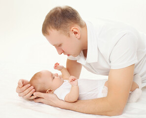 Portrait of young father with his sleeping baby lying on bed at home