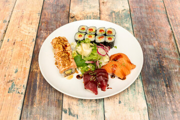 Assorted sushi combo with avocado maki and nori seaweed, Japanese white rice with vinegar, uramaki with flambéed salmon and Norwegian salmon nigiri and red tuna with soy sauce